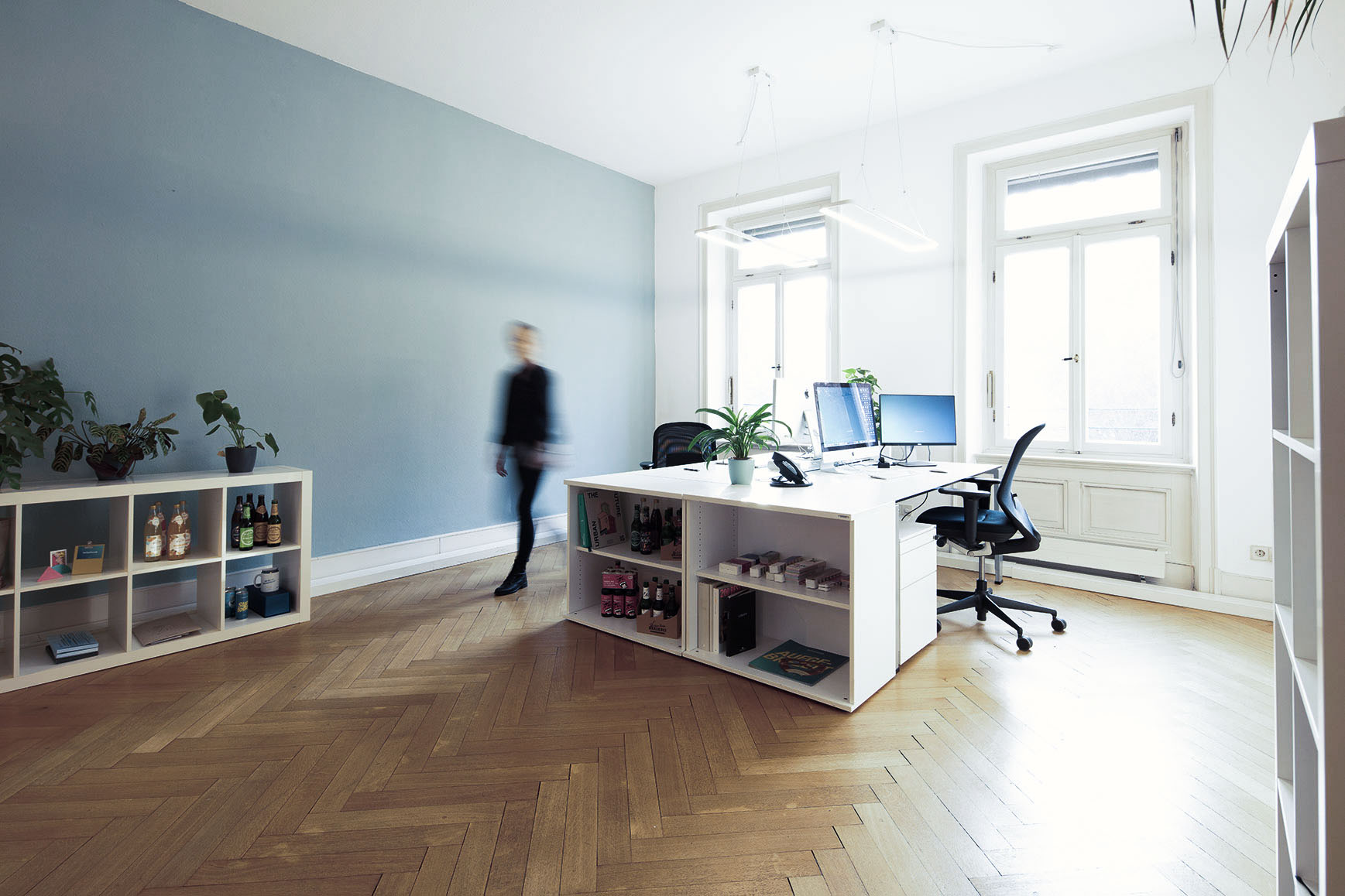 Einblick in einen Büroraum mit zwei Arbeitsplätzen und hellblauer Wand